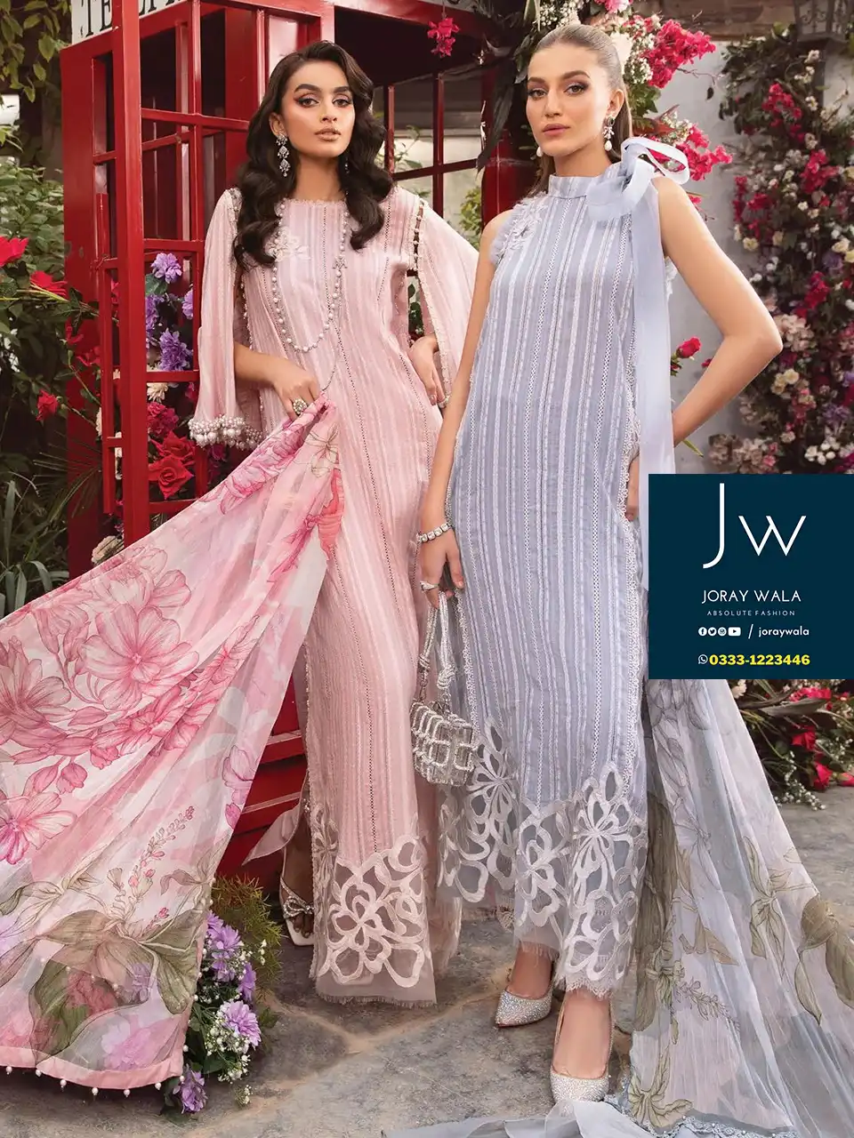 1 Model is wearing a beautiful pink color 3 pcs suit, and the 2nd model wearinng gray color suit and both standing before red color telephone booth, a lot for flowers around the model, and the suit code is MPT-2109-A